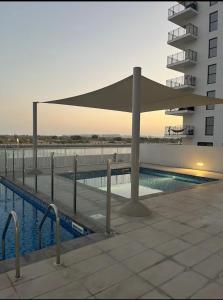 a swimming pool with a canopy next to a building at Chez Teo in Abu Dhabi