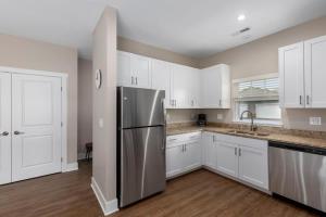 a kitchen with white cabinets and a stainless steel refrigerator at Modern 2BR & 2BA New Build Condo w Garage & Patio in Grandville