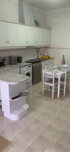 een keuken met witte kasten, een tafel en een wastafel bij Casa do Omega do Foz in Foz do Arelho