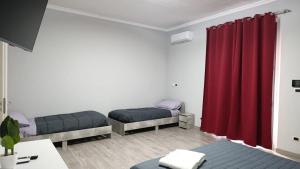 a room with two beds and a red curtain at Suites GREY in centro Randazzo in Randazzo