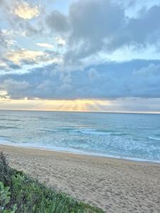 a beach with a cloudy sky and the ocean at 204 L'escalier Cabanas- Beach front paradise in Amanzimtoti