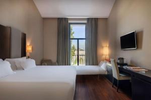 a hotel room with two beds and a desk and a window at NH Collection Palacio de Aranjuez in Aranjuez +59 photos