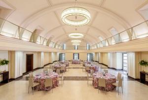 a banquet hall with tables and chairs and a chandelier at NH Collection Palacio de Aranjuez in Aranjuez