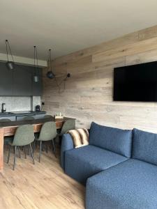 Una sala de estar con un sofá azul y un televisor en Boutique apartment Chaberton view - R16, en San Sicario