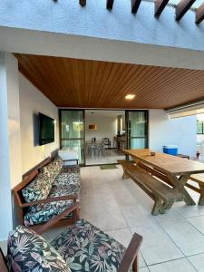 a living room with a wooden table and benches at Cobertura 3Q ILOA Barra de S Miguel Castelo B Temporada in Barra de São Miguel