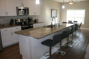 a kitchen with a large island with bar stools at Modern 2BR & 2BA Condo with Garage & Patio in Grandville