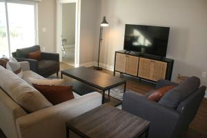 a living room with couches and a flat screen tv at Modern 2BR & 2BA Condo with Garage & Patio in Grandville