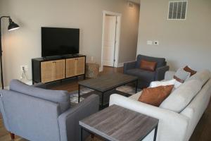 a living room with two couches and a flat screen tv at Modern 2BR & 2BA Condo with Garage & Patio in Grandville +2 photos