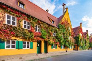 a yellow building covered in ivy on a street at Chic 2-room apartment in the historic cathedral district in Augsburg