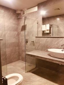 een badkamer met douche, wastafel en toilet bij Cadillac Hotel in Islamabad