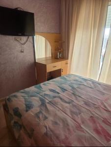 a bedroom with a bed and a desk and a television at Residence kettani in Bouznika