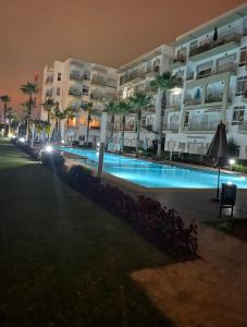 a large apartment building with a swimming pool at night at Residence kettani in Bouznika