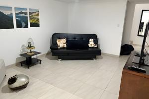 a living room with a black couch and a table at Espacioso y Elegante en Milán in Manizales