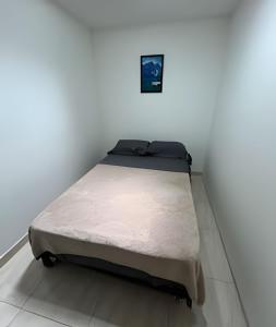a bed in a room with a white wall at Espacioso y Elegante en Milán in Manizales +1 photo