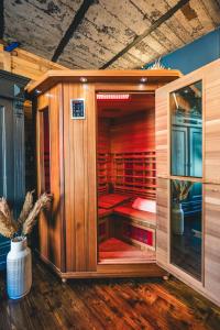 una sauna de madera con puerta de cristal en una habitación en L'Atelier - Gîte chaleureux et relaxant, en Saint-Hubert