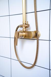 a shower hose attached to a white tiled wall at Gastenverblijf Hunsingo in Winsum +7 photos