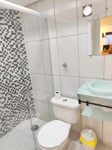 ein weißes Badezimmer mit Toilette und Dusche in der Unterkunft House in Downtown East Beach with Air Conditioning in Pontal do Paraná