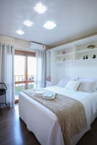 a white bedroom with a large bed and a window at Casa Petri Gramado in Gramado