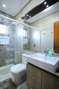 a bathroom with a sink and a toilet and a mirror at Casa Petri Gramado in Gramado