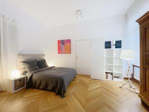 a white bedroom with a bed and a wooden floor at Strasbourg Tivoli in Strasbourg