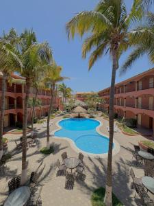 a resort with a pool and palm trees and chairs at Estancia Real Los Cabos in Cabo San Lucas