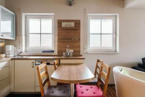 a small kitchen with a wooden table and two windows at Chic y cozy Schwaunter in Untermeitingen
