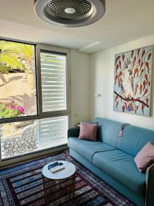 een woonkamer met een blauwe bank en 2 ramen bij AMBER APARTMENTS - PINK STUDIO in Morro del Jable