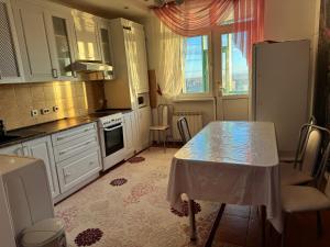 a kitchen with a table and a refrigerator at Актобе ажары in Aktobe