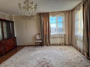a living room with a chandelier and a chair at Актобе ажары in Aktobe