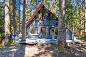 a blue tiny house in the woods at Luxury A-Frame with Hot Tub, Fireplace & Firepit in Skykomish