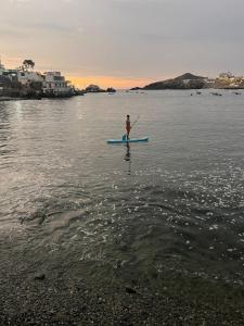 a man standing on a paddle board in the water at Departamento en malecon acogedor in San Bartolo +7 photos