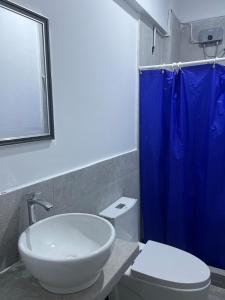 a bathroom with a white sink and a blue shower curtain at Departamento en malecon acogedor in San Bartolo