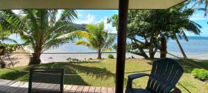 a view of a beach with a chair and the ocean at Le Neliza Beach Lodge Raiatea in Opoa