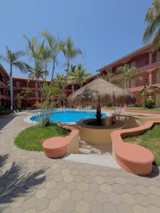 a resort with a pool and a straw umbrella and benches at Estancia Real Los Cabos in Cabo San Lucas