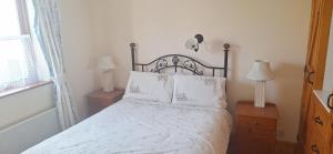 ein Schlafzimmer mit einem Bett mit weißen Laken und Kissen in der Unterkunft Cottage by the sea in Enniscrone