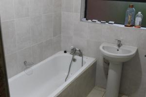 a bathroom with a tub and a sink and a toilet at Golf Course Apartment in Maseru +12 photos