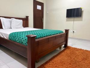 a bedroom with a bed with a television on the wall at Beatrice court in Accra