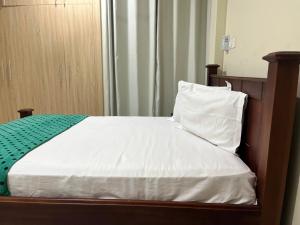 a bed with a wooden headboard and white sheets and pillows at Beatrice court in Accra +2 photos