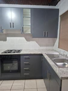 a kitchen with gray cabinets and a sink at Golf Course Apartment in Maseru