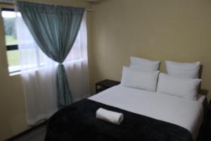 a bedroom with a large white bed with a window at Golf Course Apartment in Maseru