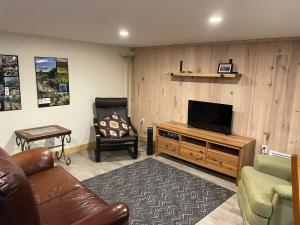 een woonkamer met een bank en een televisie bij La forêt nourricière in La Tuque