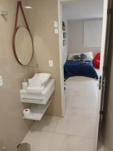 a bathroom with a sink and a mirror and a bed at Hospedagem e Coworking - suítes in Anápolis +8 photos