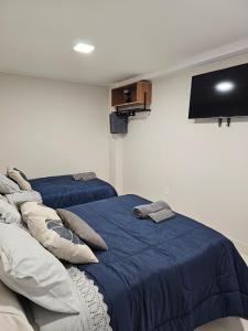 Un dormitorio con dos camas y un televisor de pantalla plana. en Hospedagem e Coworking - suítes, en Anápolis