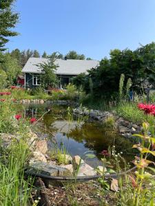 een tuin met een vijver voor een huis bij La forêt nourricière in La Tuque