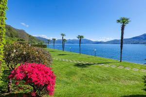 a park with flowers and palm trees and a body of water at Yachting Residence in Ghiffa
