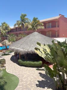 a resort with a grass roofed pavilion next to a building at Estancia Real Los Cabos in Cabo San Lucas