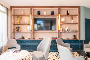 胡安莱潘Hôtel CASA MOHO - Juan-Les-Pins的有桌椅和电视的房间