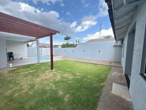 un patio trasero con piscina y valla en Casa Foz do Iguaçu Ipê, en Foz do Iguaçu