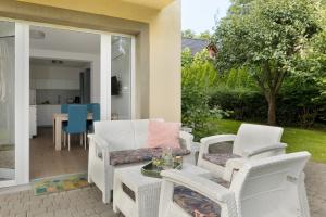 a patio with white wicker chairs and a table at Villa LILIA in Międzywodzie