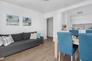 a living room with a couch and a table with blue chairs at Villa LILIA in Międzywodzie